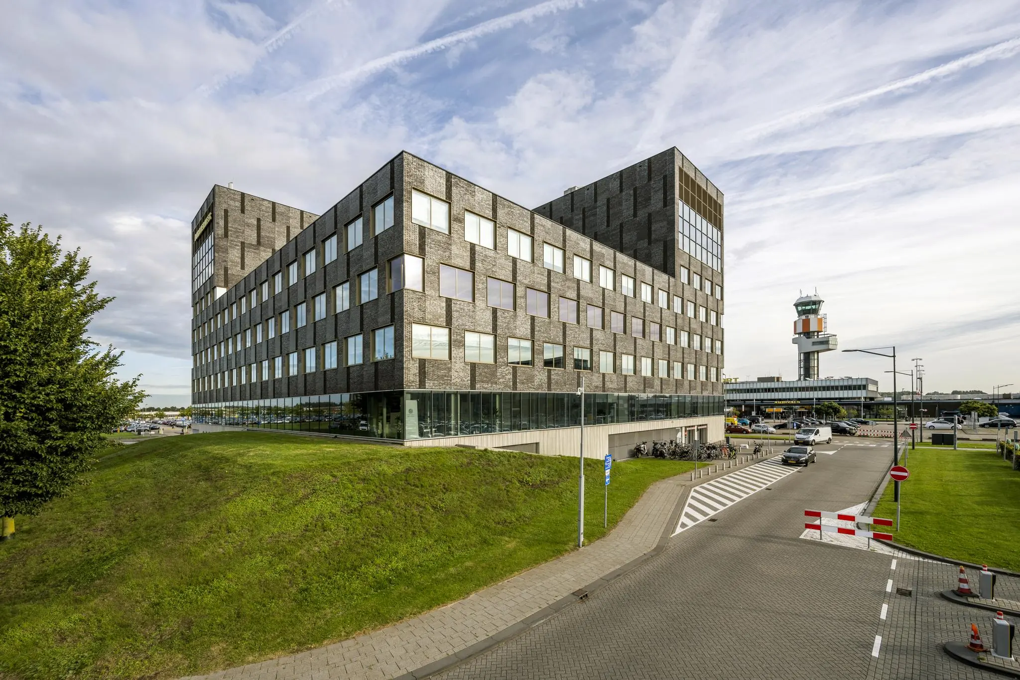 Modern kantoorgebouw aan het Airportplein bij Rotterdam The Hague Airport met verkeerstoren op de achtergrond.